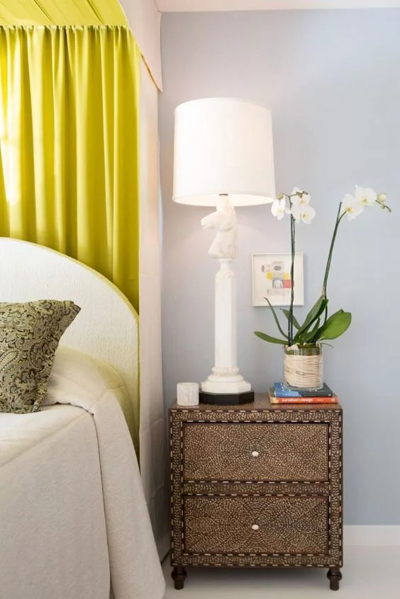 The focal point is a nightstand with a patterned designed topped with a tall white lamp styled with a knight from a chess set.  
