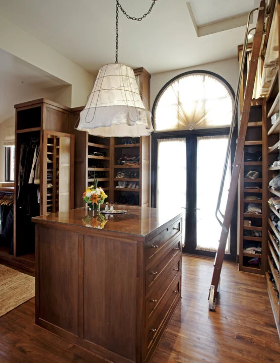 An open closet featuring wood shelves and a wooden dresser. Items on the shelves are neatly arranged.