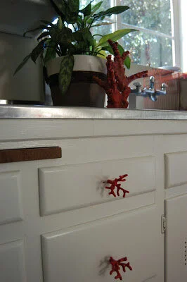 Cabinet hardware can have a big reward. These white cabinets have knobs that look like red branches.