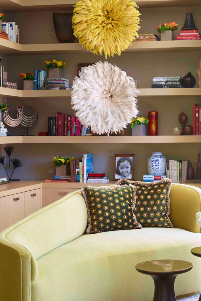 Photo of a love seat in front a built in bookshelf.  The shelf has two large flowers hanging as art.
