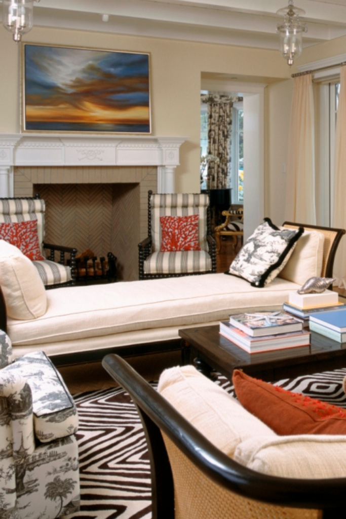 An eclectic living room with a chaise as a focal point.  A painting of a sunset hangs above the fireplace.